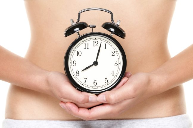 Biological clock ticking - woman holding clock in front of stoma